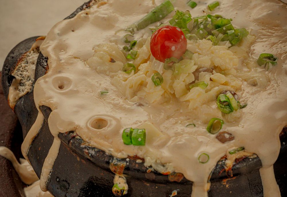Feijão verde cremoso na panela preta, com queijo e cheiro-verde