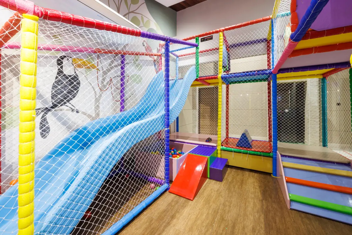 Espaço kids com escorregador azul e mural de tucano