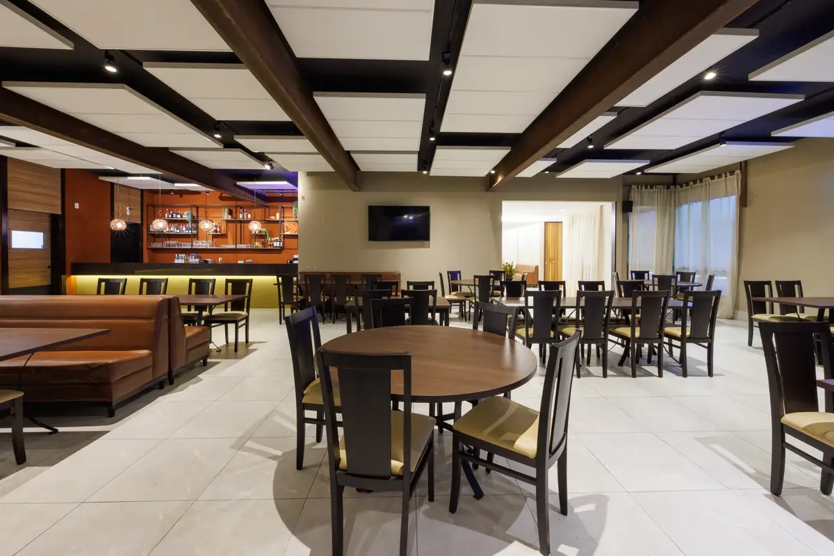 Salão 3, com mesa redonda em primeiro plano e o bar ao fundo